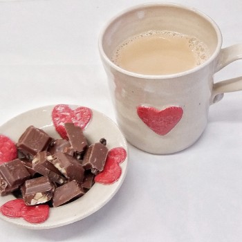red heart mug with tea and bon bon with chocolate